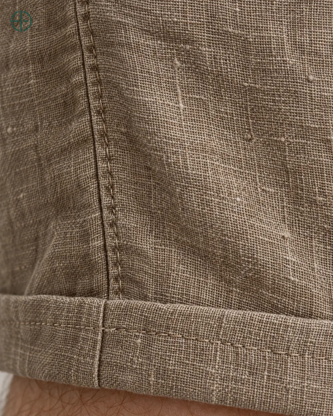 Bermuda 100% Linho Belga Masculina, cor Marrom, Detalhe do tecido e da barra no modelo, em estúdio profissional com fundo cinza ostra.
