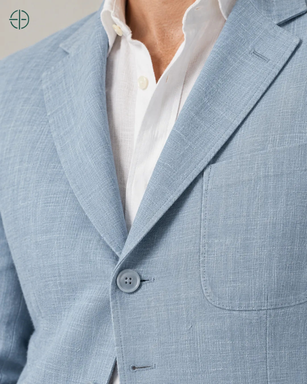 Blazer 100% Linho Belga, cor Azul, macro do produto no modelo, em estúdio profissional com fundo cinza ostra.