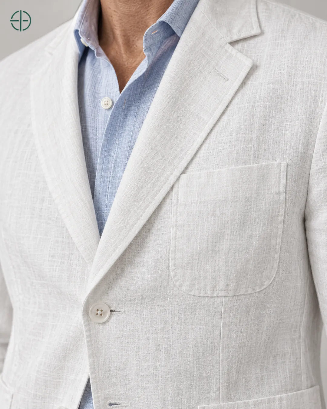 Blazer 100% Linho Belga, cor Branco, macro do produto no modelo, em estúdio profissional com fundo cinza ostra.