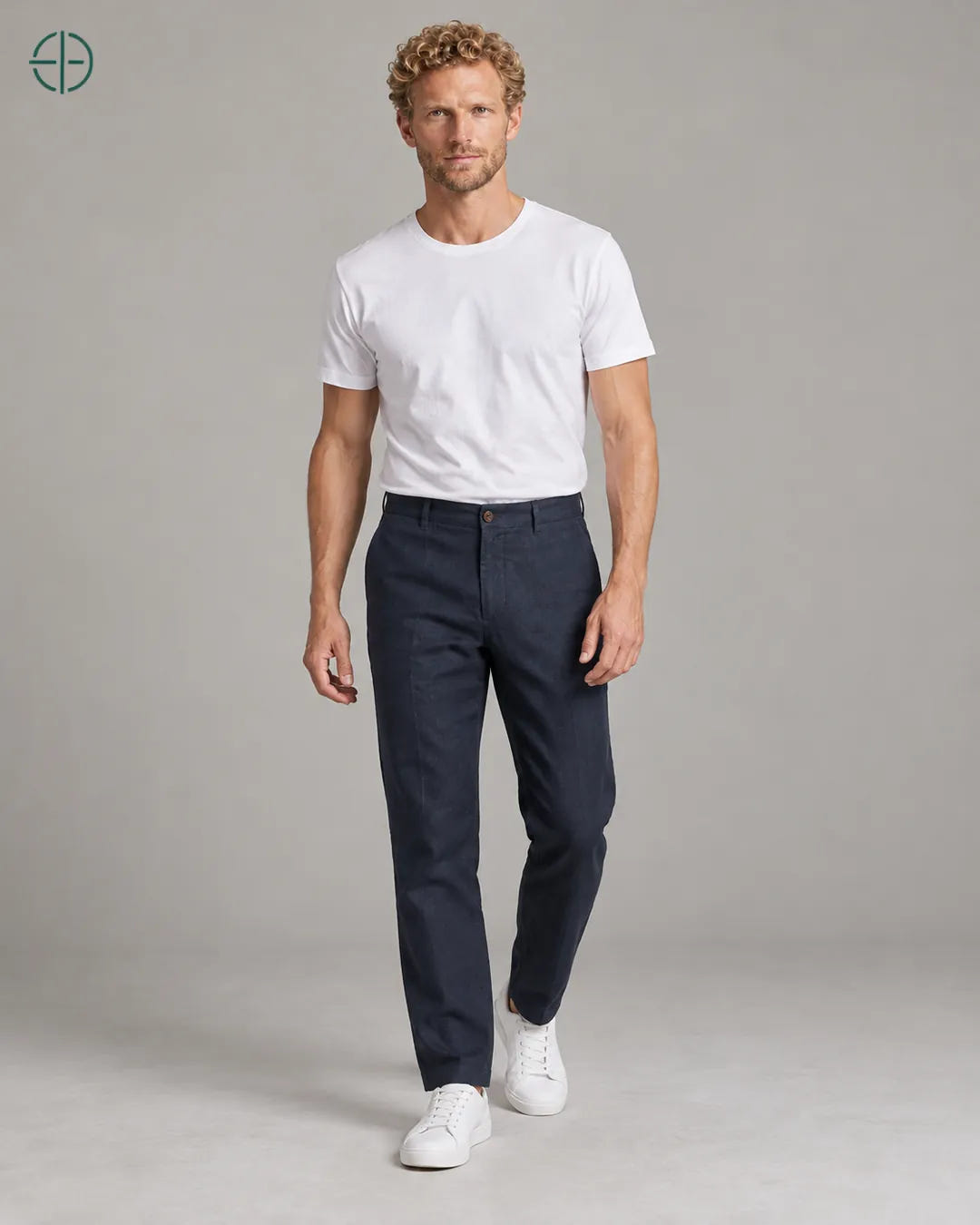 Calça 100% Linho Belga Masculina, cor Azul Marinho, Mesmo modelo e roupa em pose natural de três quartos, mostrando o caimento da peça, em estúdio profissional com fundo cinza ostra.