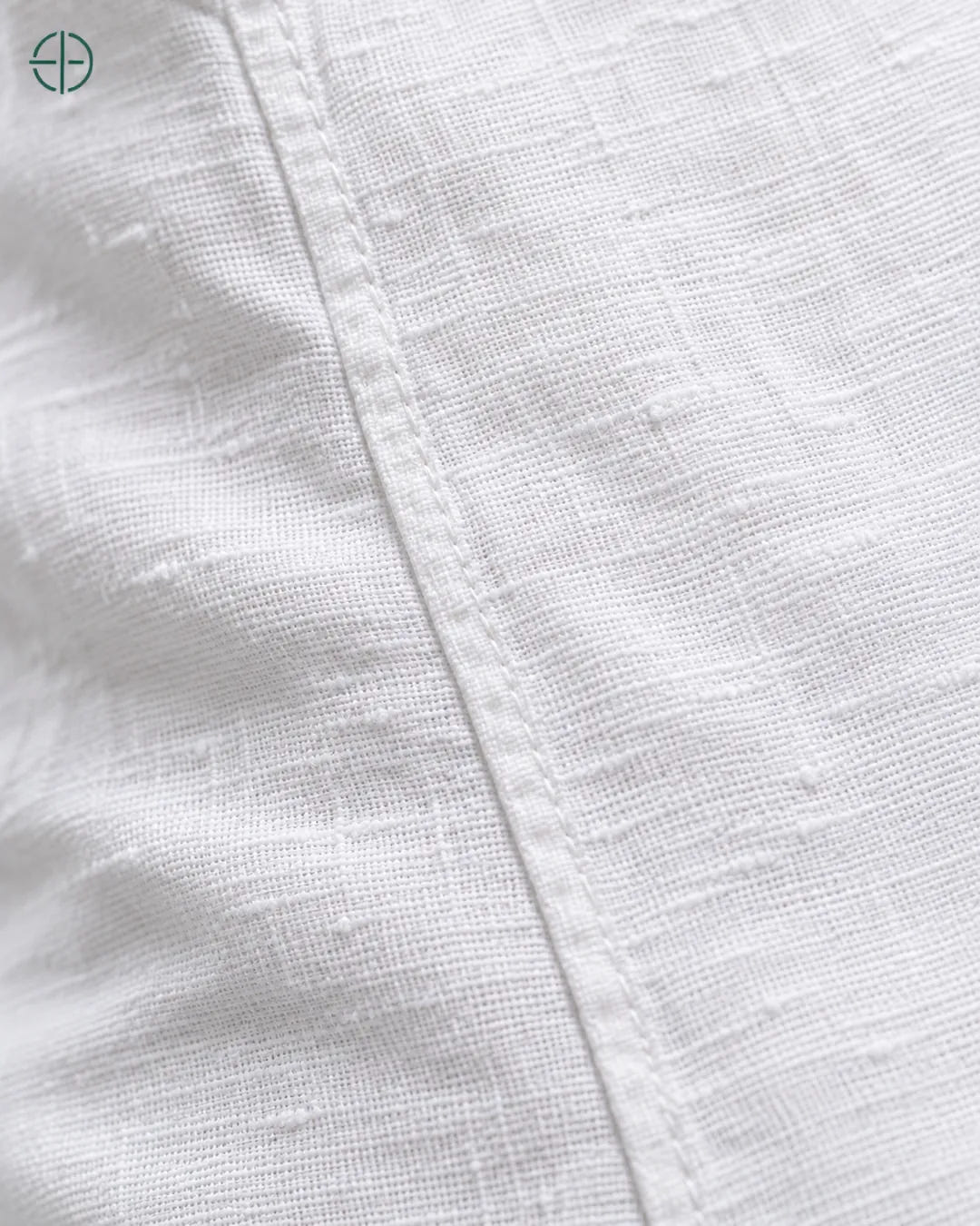 Camisa 100% Linho Belga Manga Curta, cor Branco, macro do produto no modelo, em estúdio profissional com fundo cinza ostra.