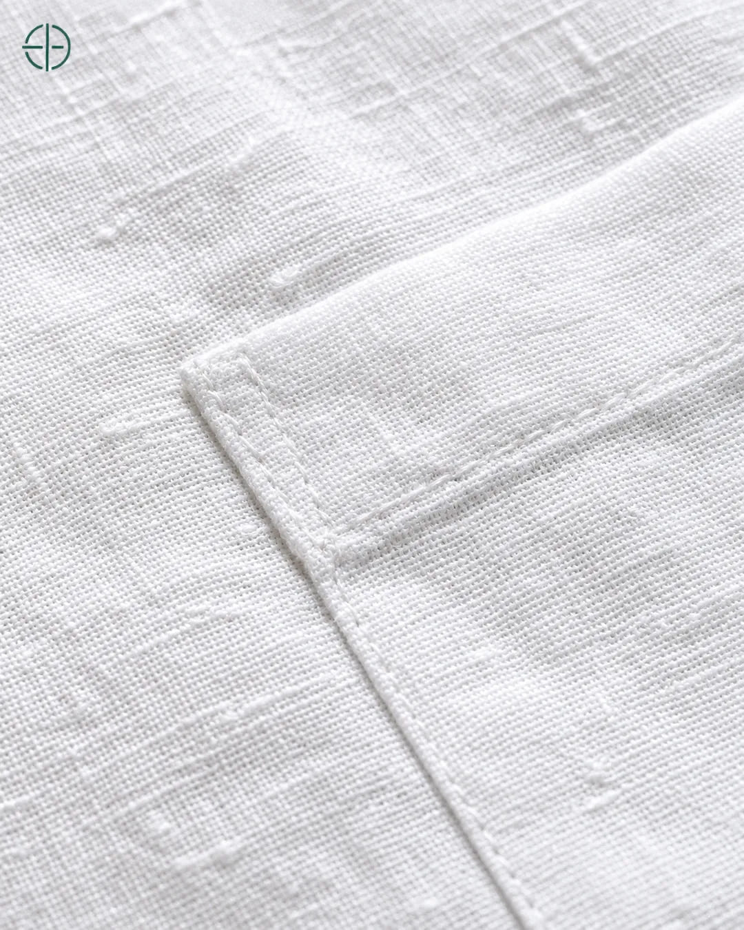 Camisa 100% Linho Belga Manga Curta, cor Branco, Detalhe aproximado do tecido e da costura no modelo, mostrando textura real, em estúdio profissional com fundo cinza ostra.