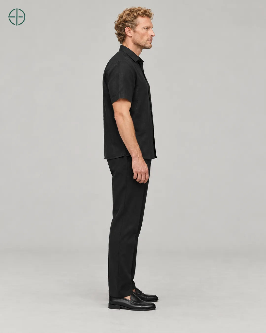 Camisa 100% Linho Belga Manga Curta, cor Preto, mesmo modelo e roupa de lado, em estúdio profissional com fundo cinza ostra.
