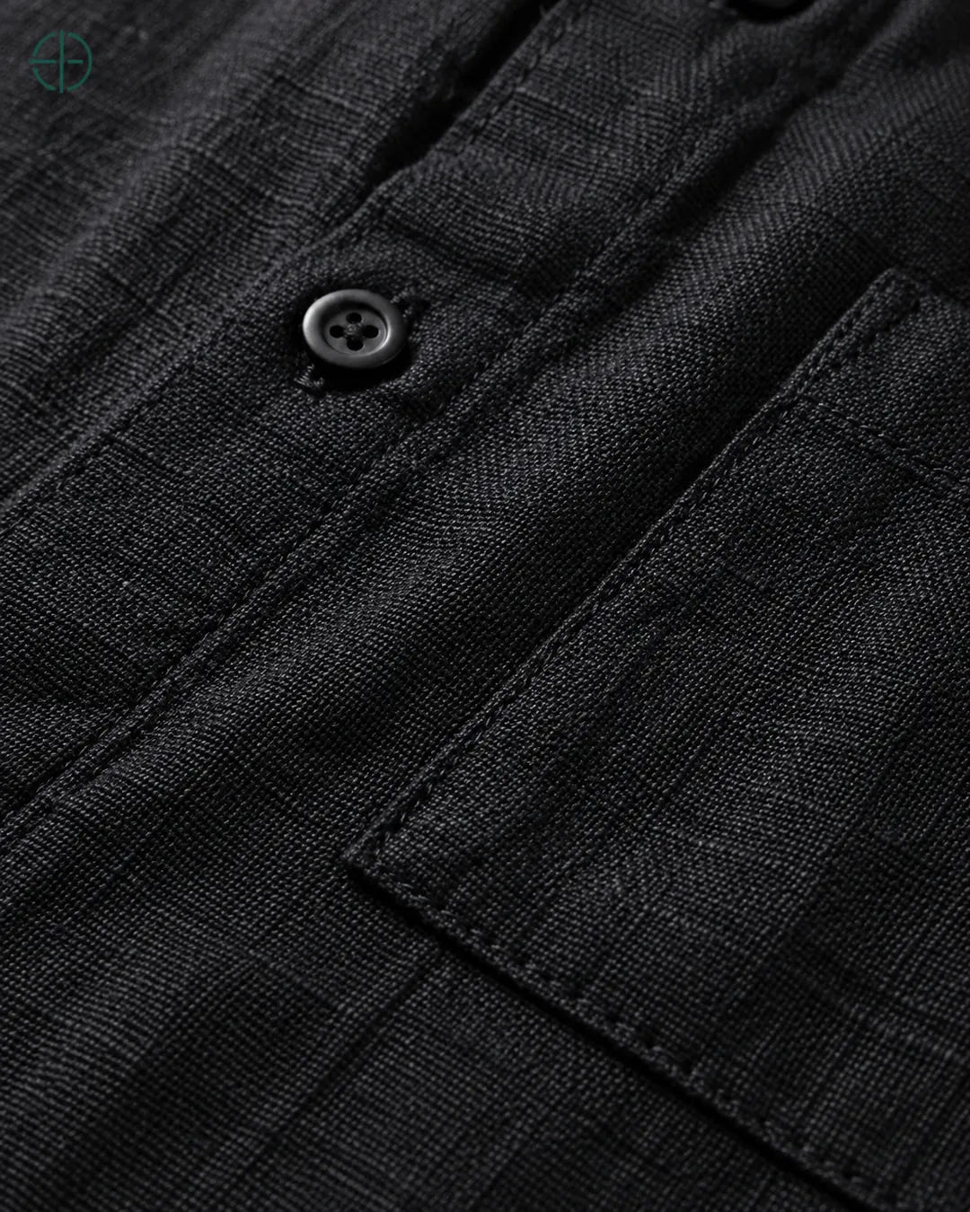 Camisa 100% Linho Belga Manga Curta, cor Preto, Detalhe aproximado do tecido e da costura no modelo, mostrando textura real, em estúdio profissional com fundo cinza ostra.