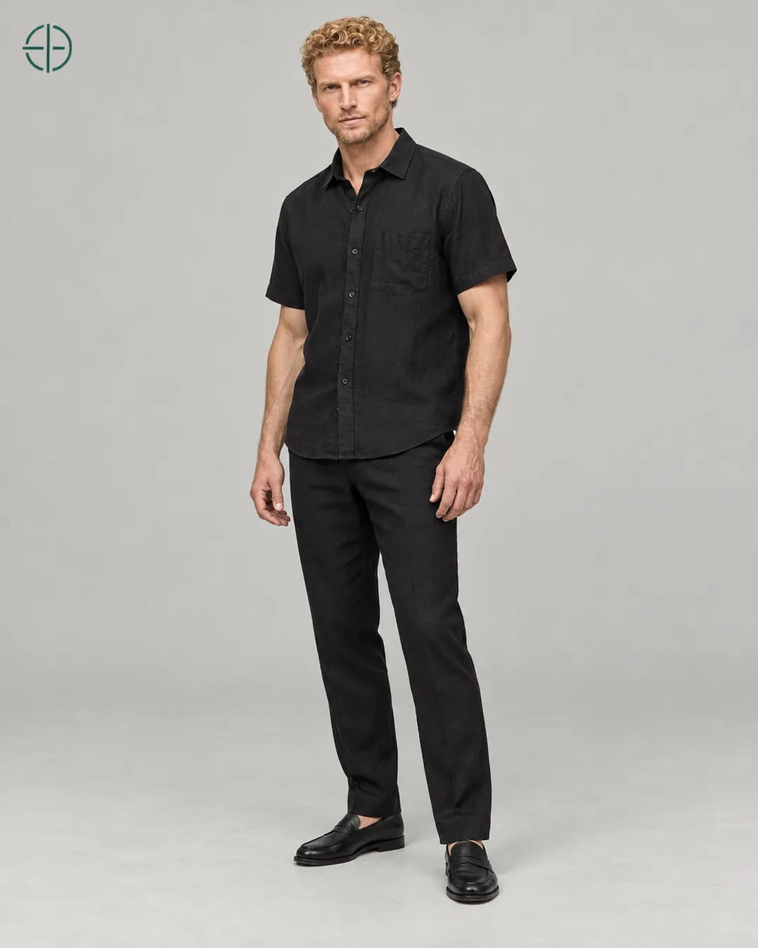 Camisa 100% Linho Belga Manga Curta, cor Preto, Mesmo modelo e roupa em pose natural de três quartos, mostrando o caimento da peça, em estúdio profissional com fundo cinza ostra.