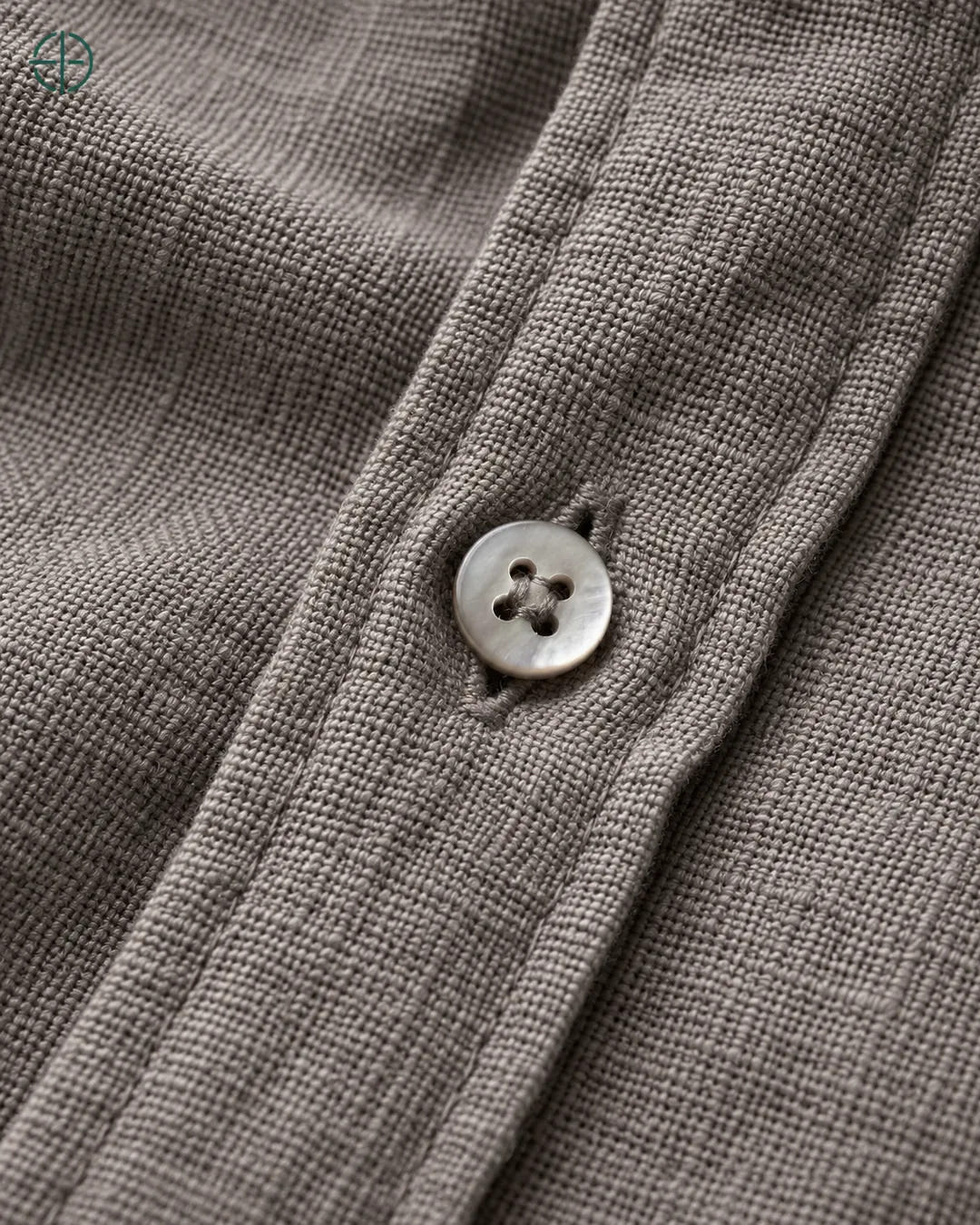 Camisa 100% Linho Belga Masculina, cor Camelo, Detalhe aproximado do tecido e da costura no modelo, mostrando textura real, em estúdio profissional com fundo cinza ostra.