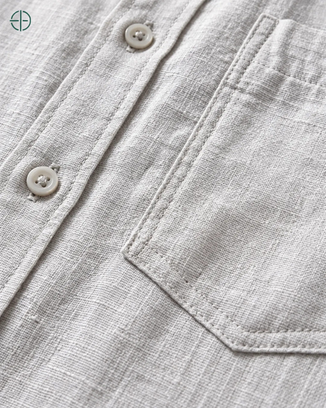 Camisa 100% Linho Belga Masculina, cor Cinza, Detalhe aproximado do tecido e da costura no modelo, mostrando textura real, em estúdio profissional com fundo cinza ostra.