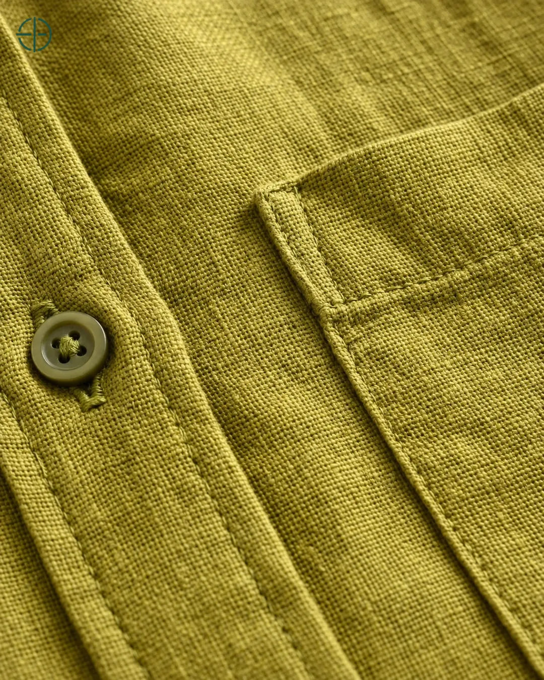 Camisa 100% Linho Belga Masculina, cor Oliva, Detalhe aproximado do tecido e da costura no modelo, mostrando textura real, em estúdio profissional com fundo cinza ostra.