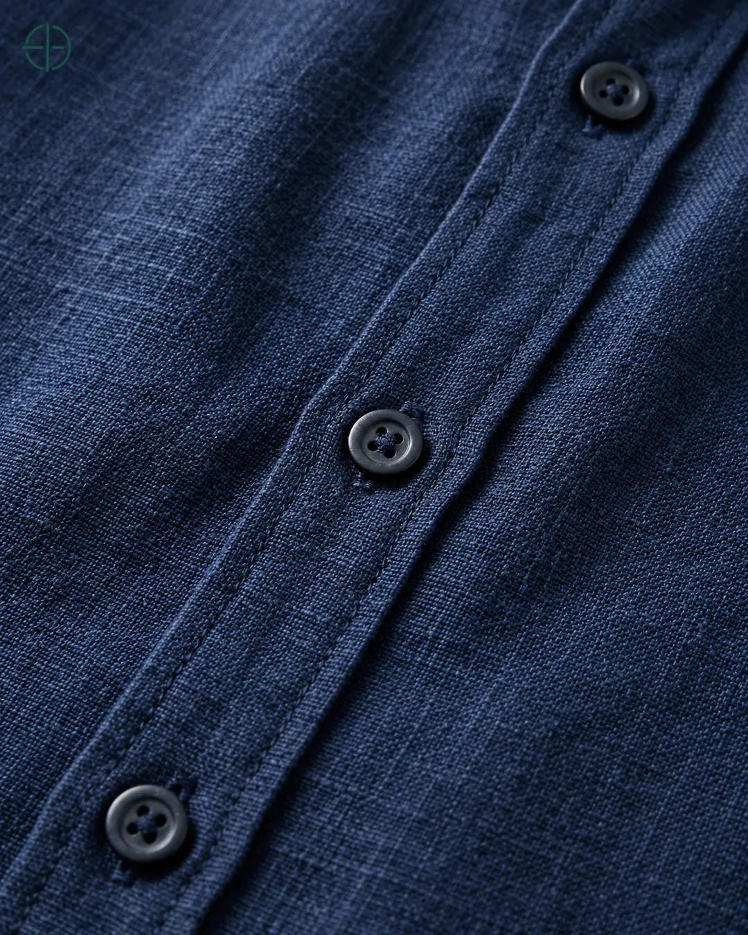 Camisa 100% Linho Belga Masculina Sem Bolso, cor Azul Marinho, Detalhe aproximado do tecido e da costura no modelo, mostrando textura real, em estúdio profissional com fundo cinza ostra.