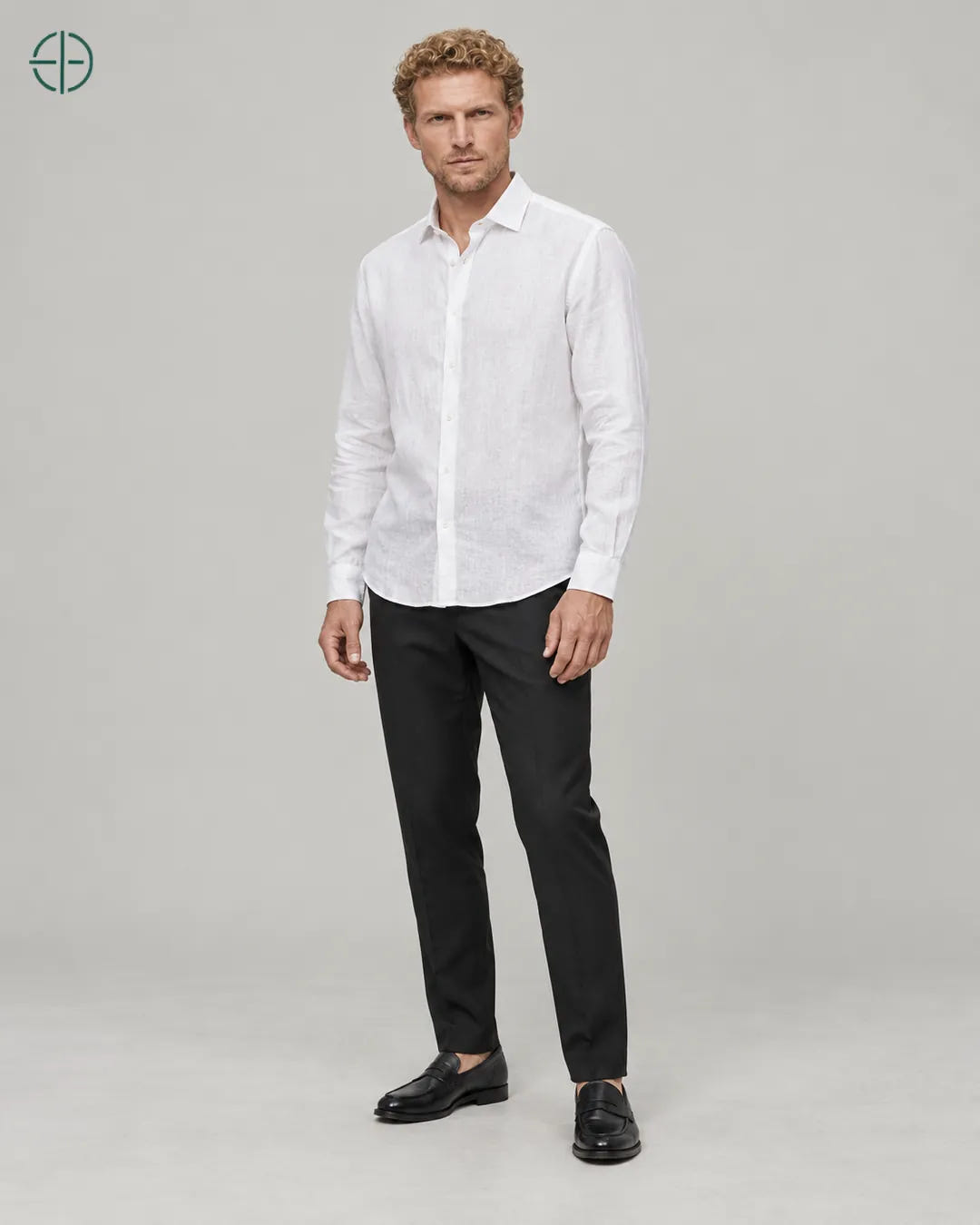 Camisa 100% Linho Belga Masculina Sem Bolso, cor Branco, Mesmo modelo e roupa em pose natural de três quartos, mostrando o caimento da peça, em estúdio profissional com fundo cinza ostra.