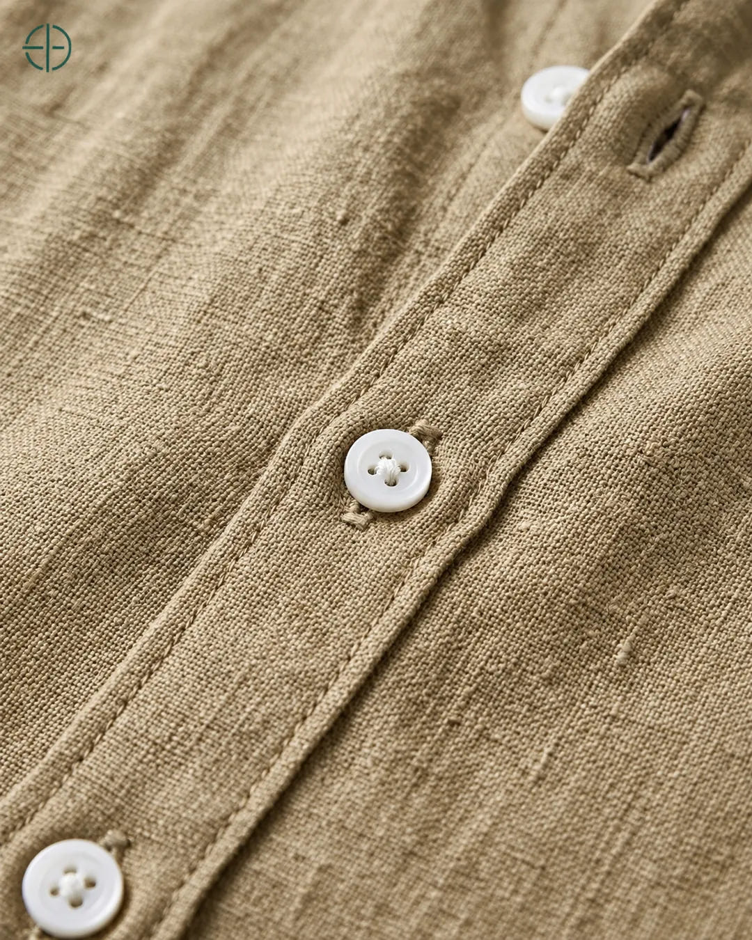 Camisa 100% Linho Belga Masculina Sem Bolso, cor Camelo, Detalhe aproximado do tecido e da costura no modelo, mostrando textura real, em estúdio profissional com fundo cinza ostra.