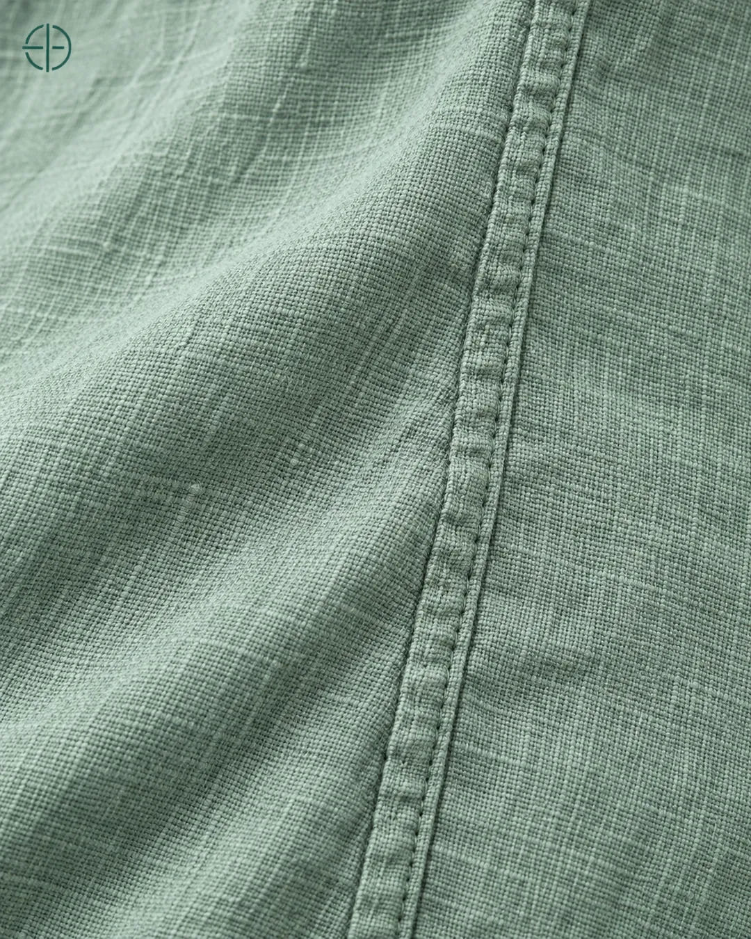 Camisa 100% Linho Belga Masculina Sem Bolso, cor Verde, macro do produto no modelo, em estúdio profissional com fundo cinza ostra.