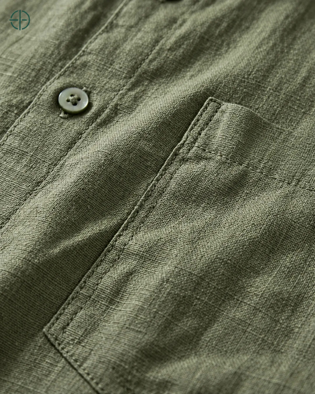 Camisa 100% Linho Belga Masculina, cor Verde, Detalhe aproximado do tecido e da costura no modelo, mostrando textura real, em estúdio profissional com fundo cinza ostra.