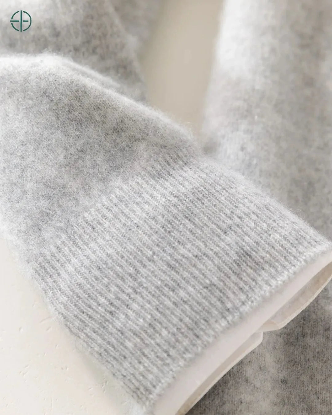 Ângulo inferior do suéter, destacando a barra e o início do corpo em caxemira.