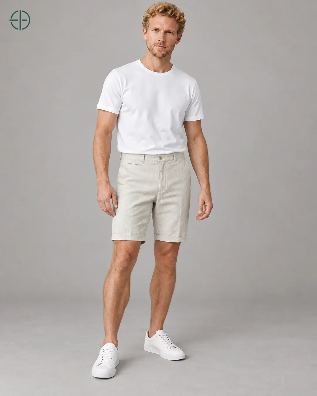 Bermuda 100% Linho Belga Masculina, cor Bege, Caimento em pose natural de três quartos, em estúdio profissional com fundo cinza ostra.