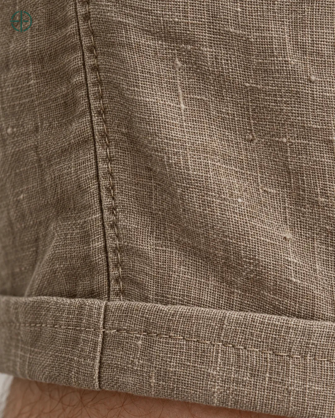 Bermuda 100% Linho Belga Masculina, cor Marrom, Detalhe do tecido e da barra no modelo, em estúdio profissional com fundo cinza ostra.