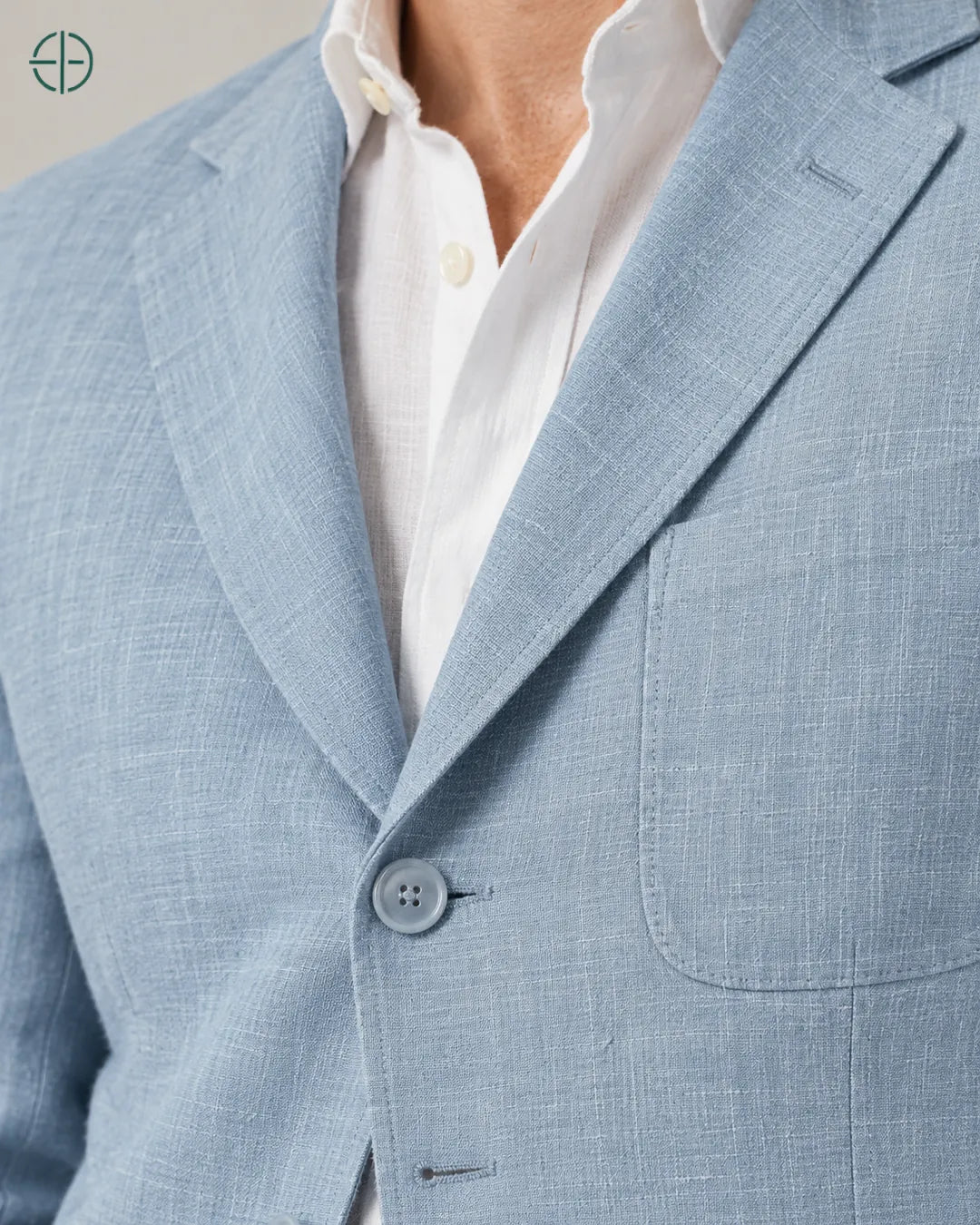 Blazer 100% Linho Belga, cor Azul, macro do produto no modelo, em estúdio profissional com fundo cinza ostra.