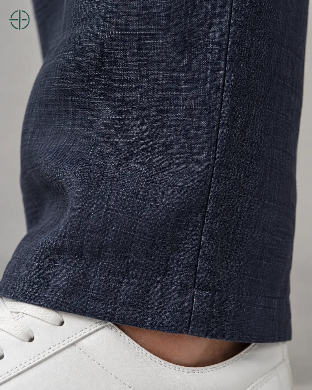 Calça 100% Linho Belga Masculina, cor Azul Marinho, Detalhe aproximado do tecido e da costura no modelo, mostrando textura real, em estúdio profissional com fundo cinza ostra.