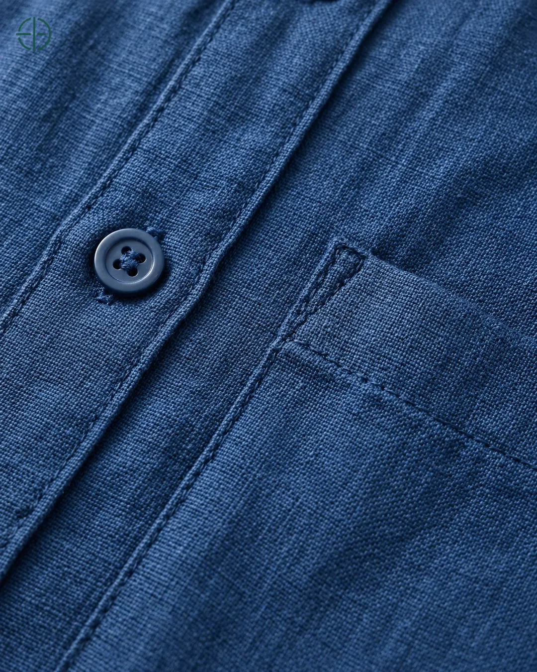 Camisa 100% Linho Belga Manga Curta, cor Azul Marinho, Detalhe aproximado do tecido e da costura no modelo, mostrando textura real, em estúdio profissional com fundo cinza ostra.