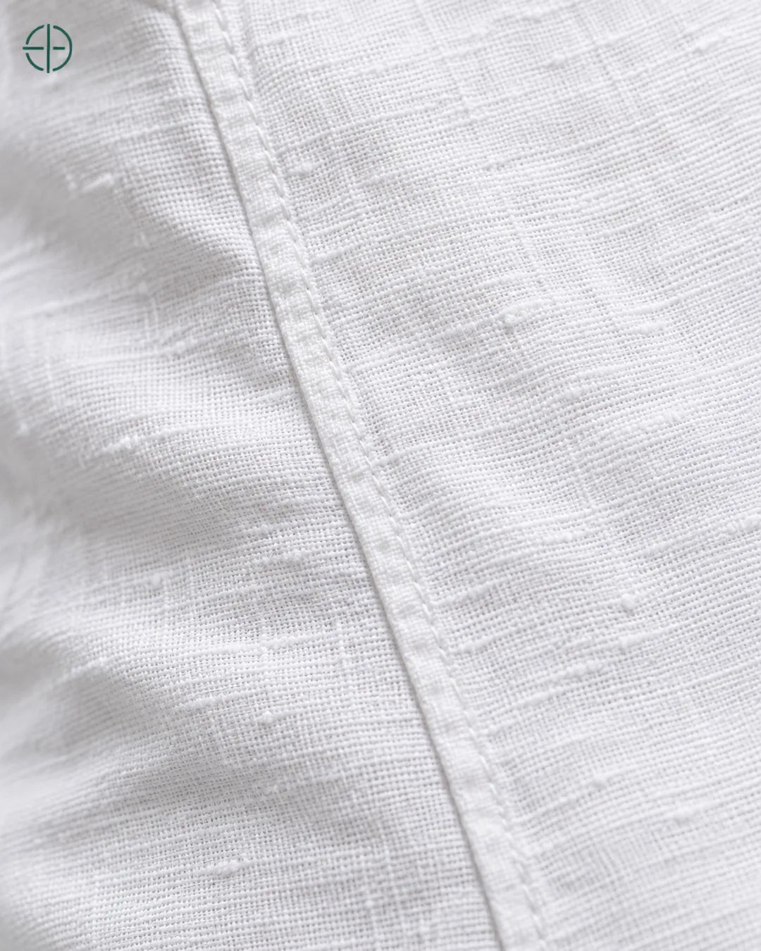 Camisa 100% Linho Belga Manga Curta, cor Branco, macro do produto no modelo, em estúdio profissional com fundo cinza ostra.