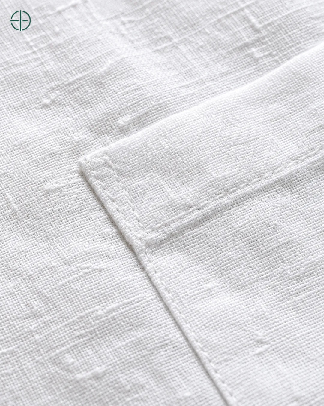 Camisa 100% Linho Belga Manga Curta, cor Branco, Detalhe aproximado do tecido e da costura no modelo, mostrando textura real, em estúdio profissional com fundo cinza ostra.