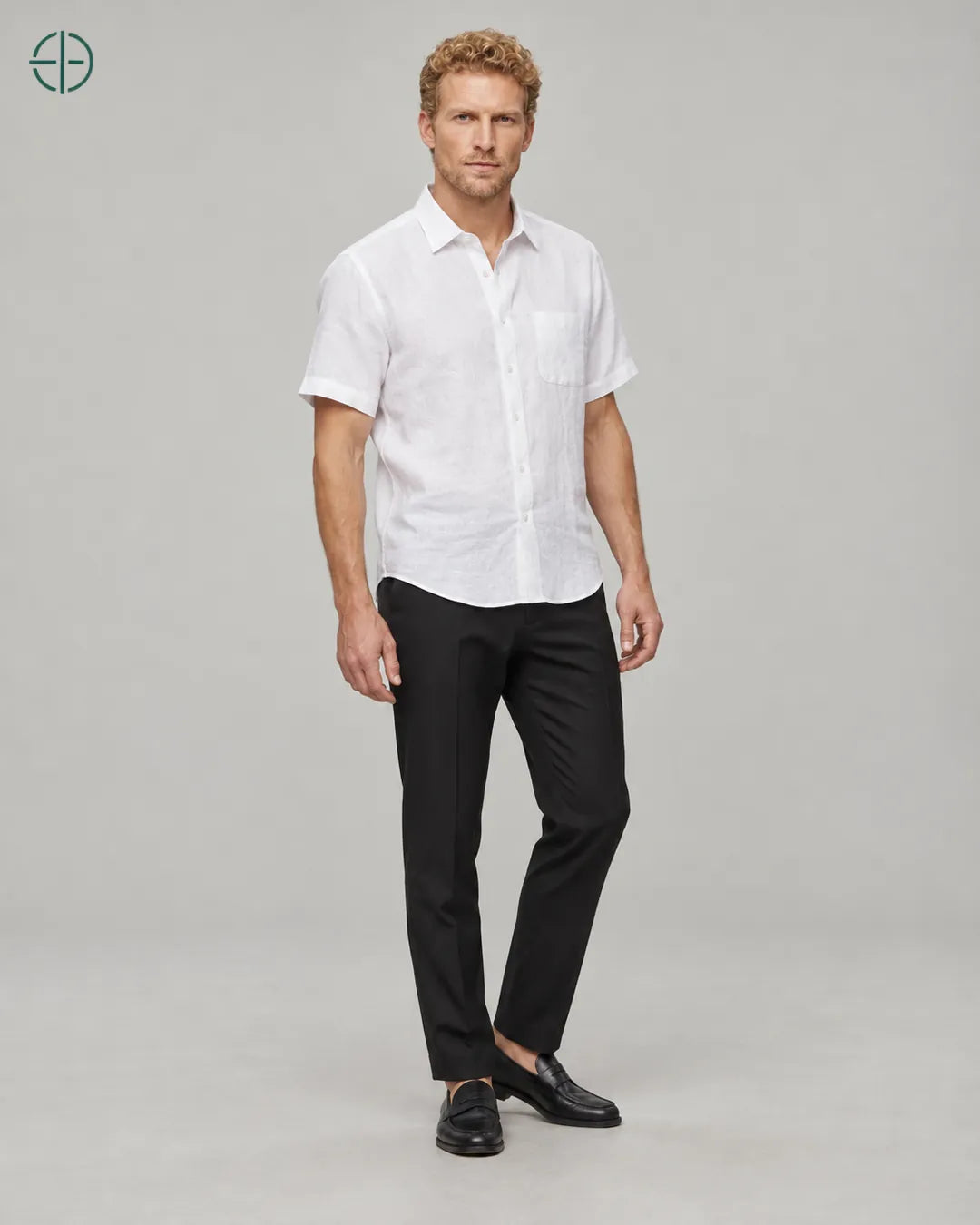 Camisa 100% Linho Belga Manga Curta, cor Branco, Mesmo modelo e roupa em pose natural de três quartos, mostrando o caimento da peça, em estúdio profissional com fundo cinza ostra.