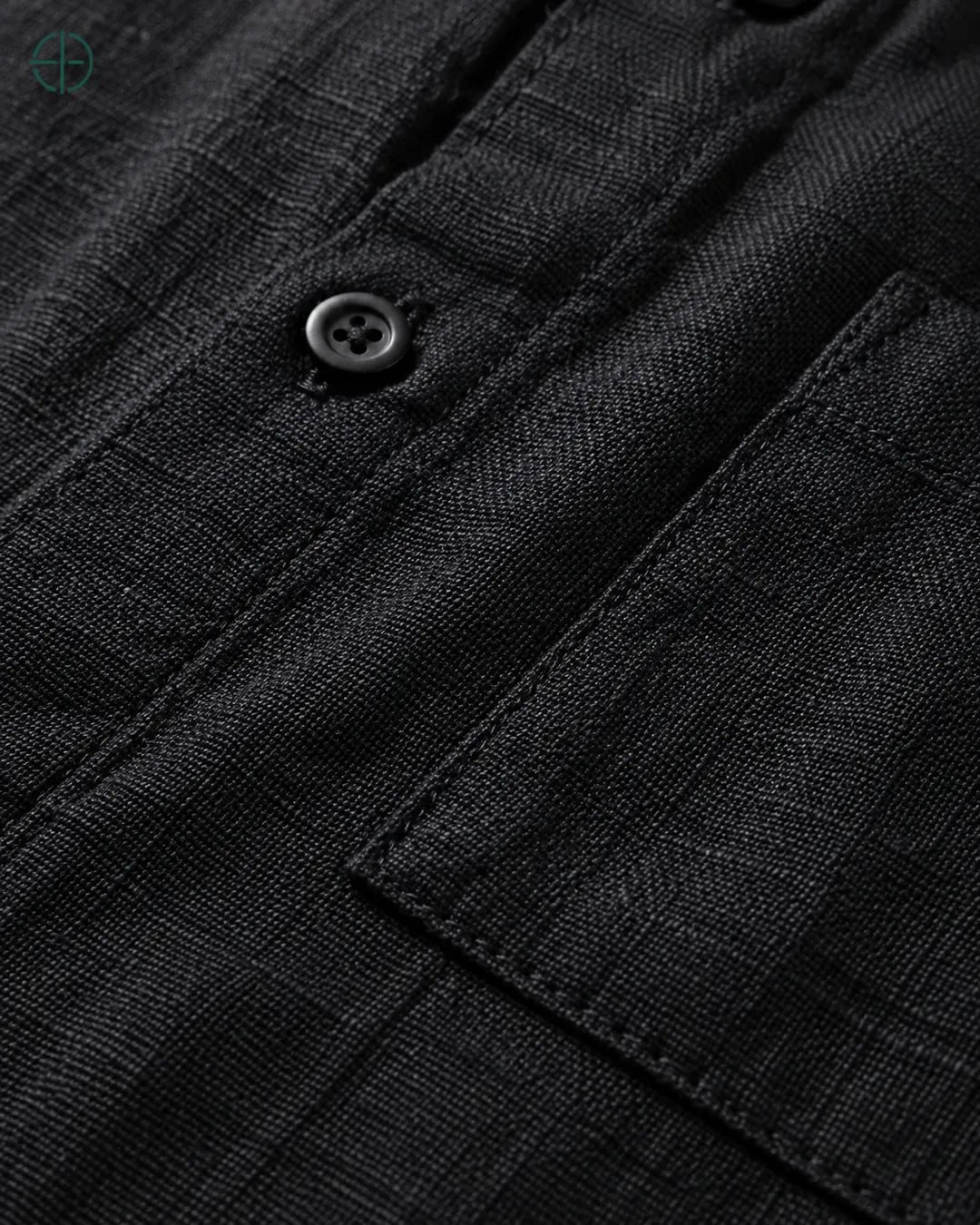 Camisa 100% Linho Belga Manga Curta, cor Preto, Detalhe aproximado do tecido e da costura no modelo, mostrando textura real, em estúdio profissional com fundo cinza ostra.