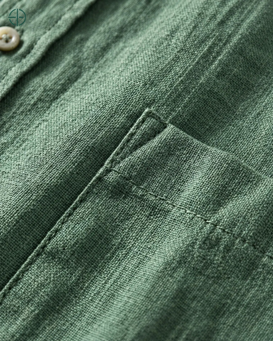 Camisa 100% Linho Belga Manga Curta, cor Verde, Detalhe aproximado do tecido e da costura no modelo, mostrando textura real, em estúdio profissional com fundo cinza ostra.