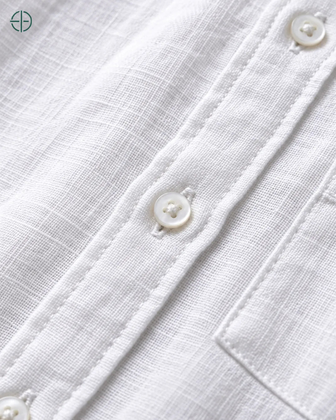 Camisa 100% Linho Belga Masculina, cor Branco, Detalhe aproximado do tecido e da costura no modelo, mostrando textura real, em estúdio profissional com fundo cinza ostra.