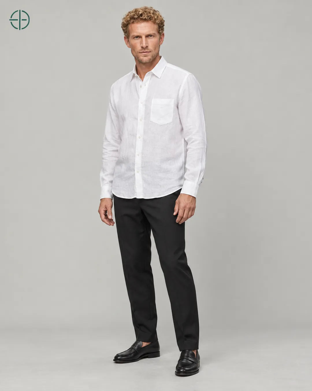 Camisa 100% Linho Belga Masculina, cor Branco, Mesmo modelo e roupa em pose natural de três quartos, mostrando o caimento da peça, em estúdio profissional com fundo cinza ostra.