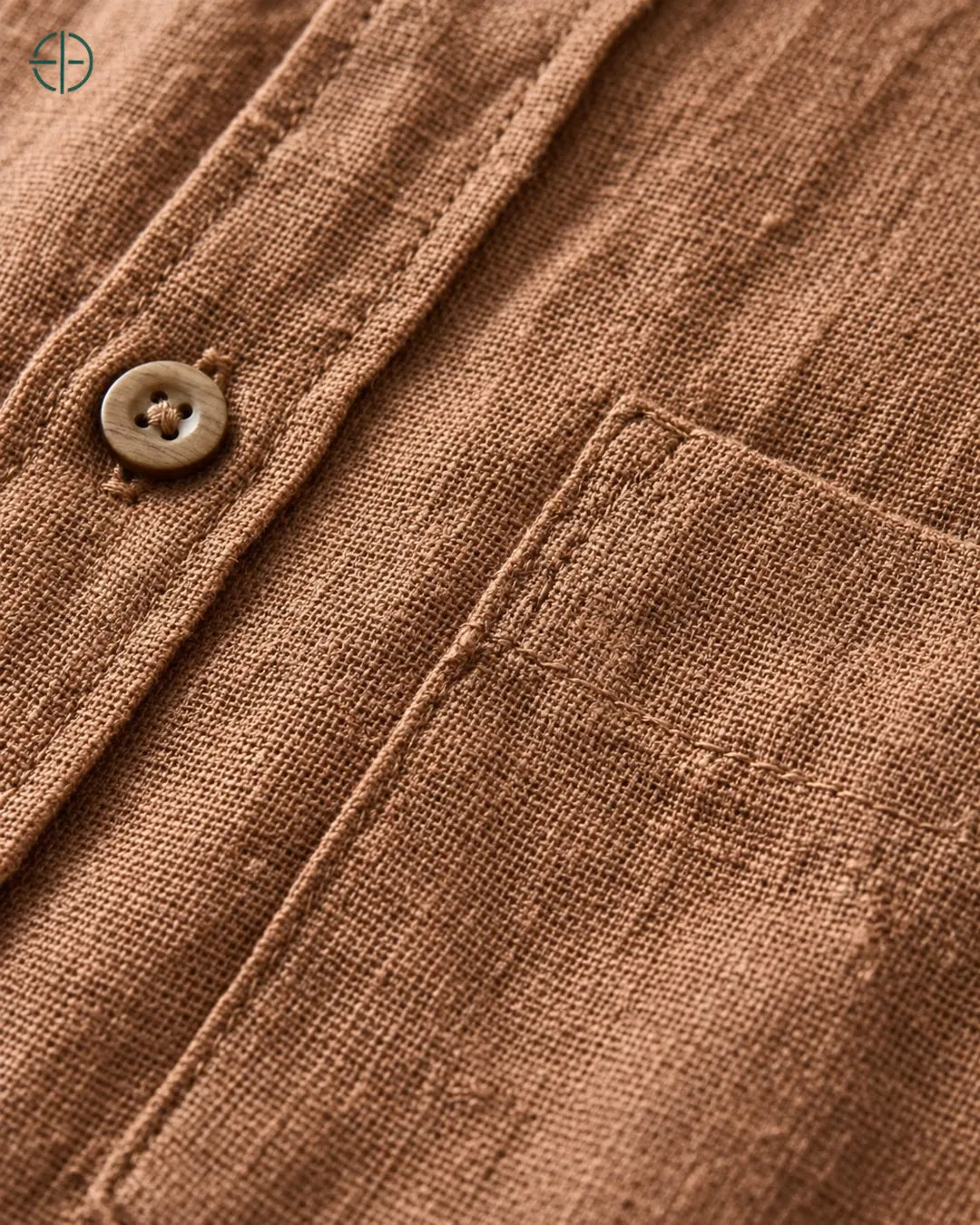 Camisa 100% Linho Belga Masculina, cor Bronze, Detalhe aproximado do tecido e da costura no modelo, mostrando textura real, em estúdio profissional com fundo cinza ostra.