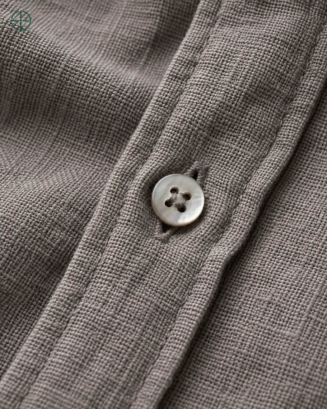 Camisa 100% Linho Belga Masculina, cor Camelo, Detalhe aproximado do tecido e da costura no modelo, mostrando textura real, em estúdio profissional com fundo cinza ostra.