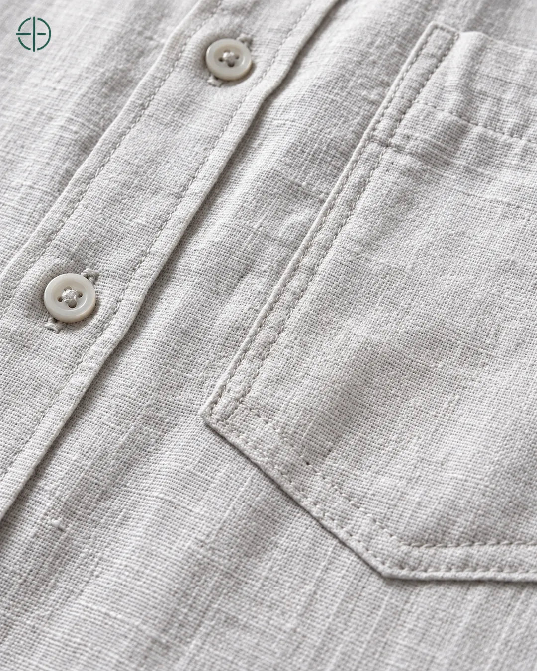 Camisa 100% Linho Belga Masculina, cor Cinza, Detalhe aproximado do tecido e da costura no modelo, mostrando textura real, em estúdio profissional com fundo cinza ostra.