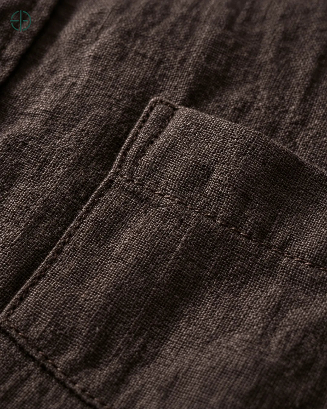 Camisa 100% Linho Belga Masculina, cor Marrom, Detalhe aproximado do tecido e da costura no modelo, mostrando textura real, em estúdio profissional com fundo cinza ostra.
