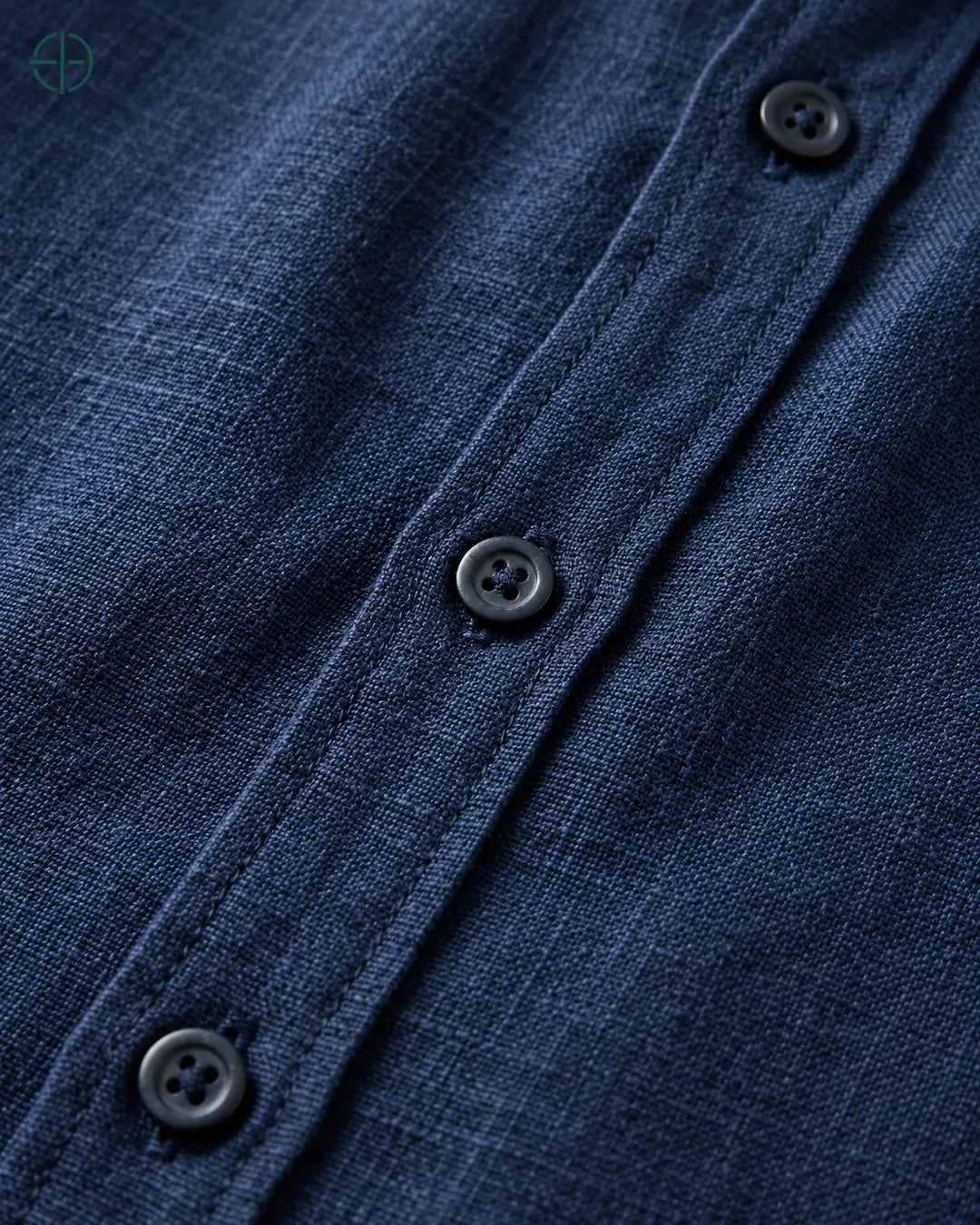 Camisa 100% Linho Belga Masculina Sem Bolso, cor Azul Marinho, Detalhe aproximado do tecido e da costura no modelo, mostrando textura real, em estúdio profissional com fundo cinza ostra.