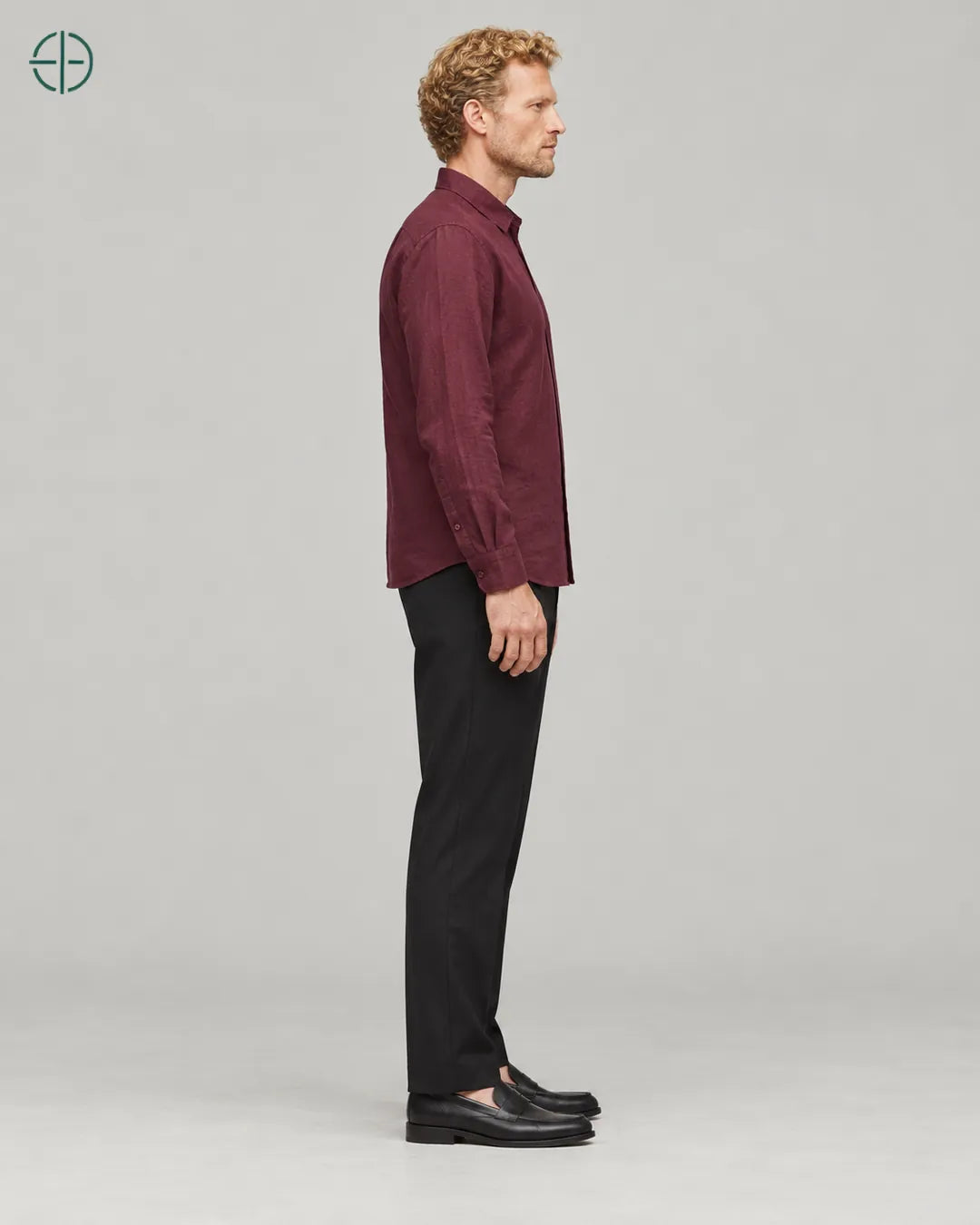 Camisa 100% Linho Belga Masculina Sem Bolso, cor Bordo, mesmo modelo e roupa de lado, em estúdio profissional com fundo cinza ostra.
