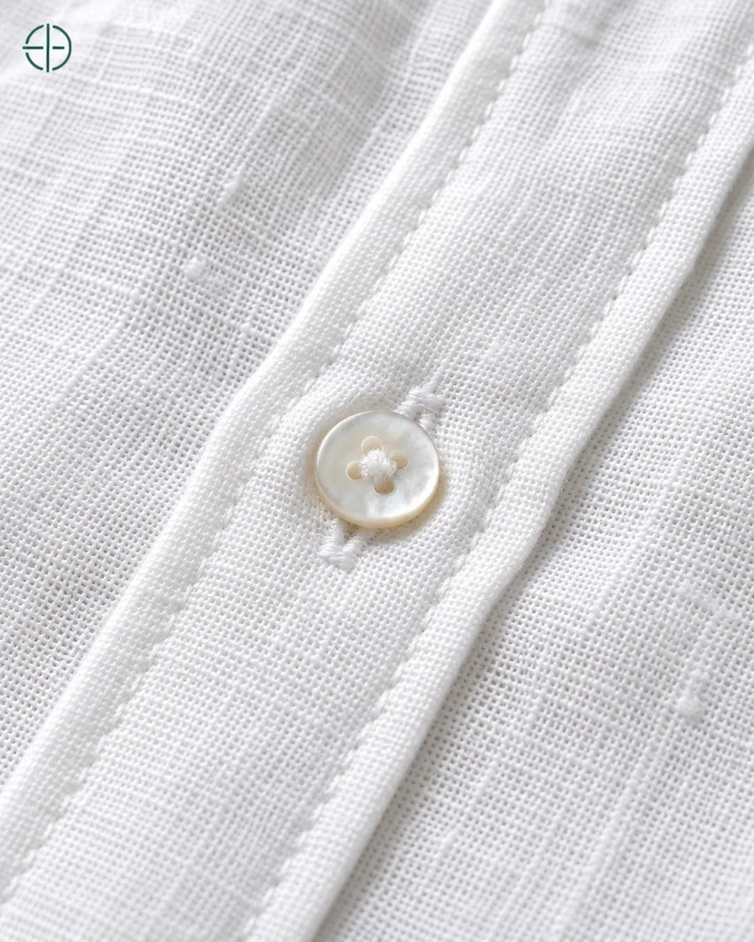 Camisa 100% Linho Belga Masculina Sem Bolso, cor Branco, Detalhe aproximado do tecido e da costura no modelo, mostrando textura real, em estúdio profissional com fundo cinza ostra.