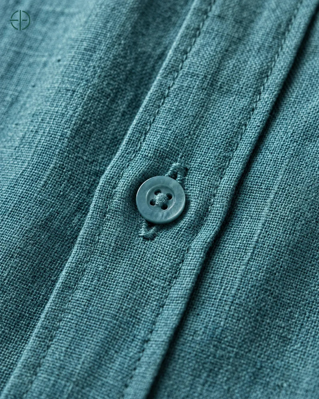 Camisa 100% Linho Belga Masculina Sem Bolso, cor Ciano, Detalhe aproximado do tecido e da costura no modelo, mostrando textura real, em estúdio profissional com fundo cinza ostra.