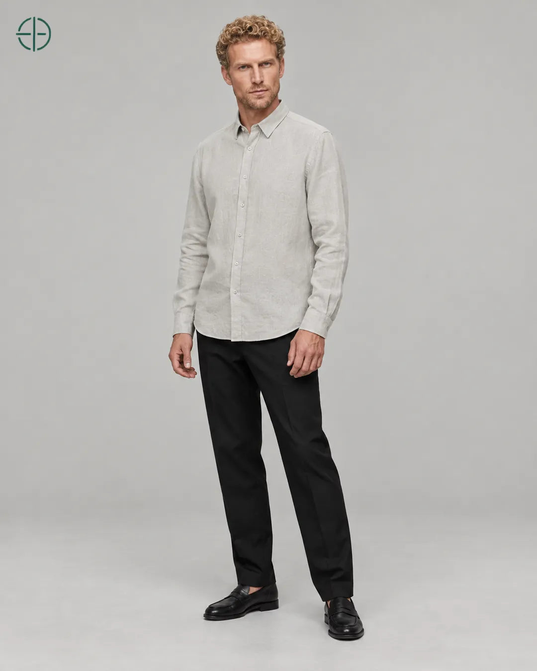 Camisa 100% Linho Belga Masculina Sem Bolso, cor Cinza, Mesmo modelo e roupa em pose natural de três quartos, mostrando o caimento da peça, em estúdio profissional com fundo cinza ostra.