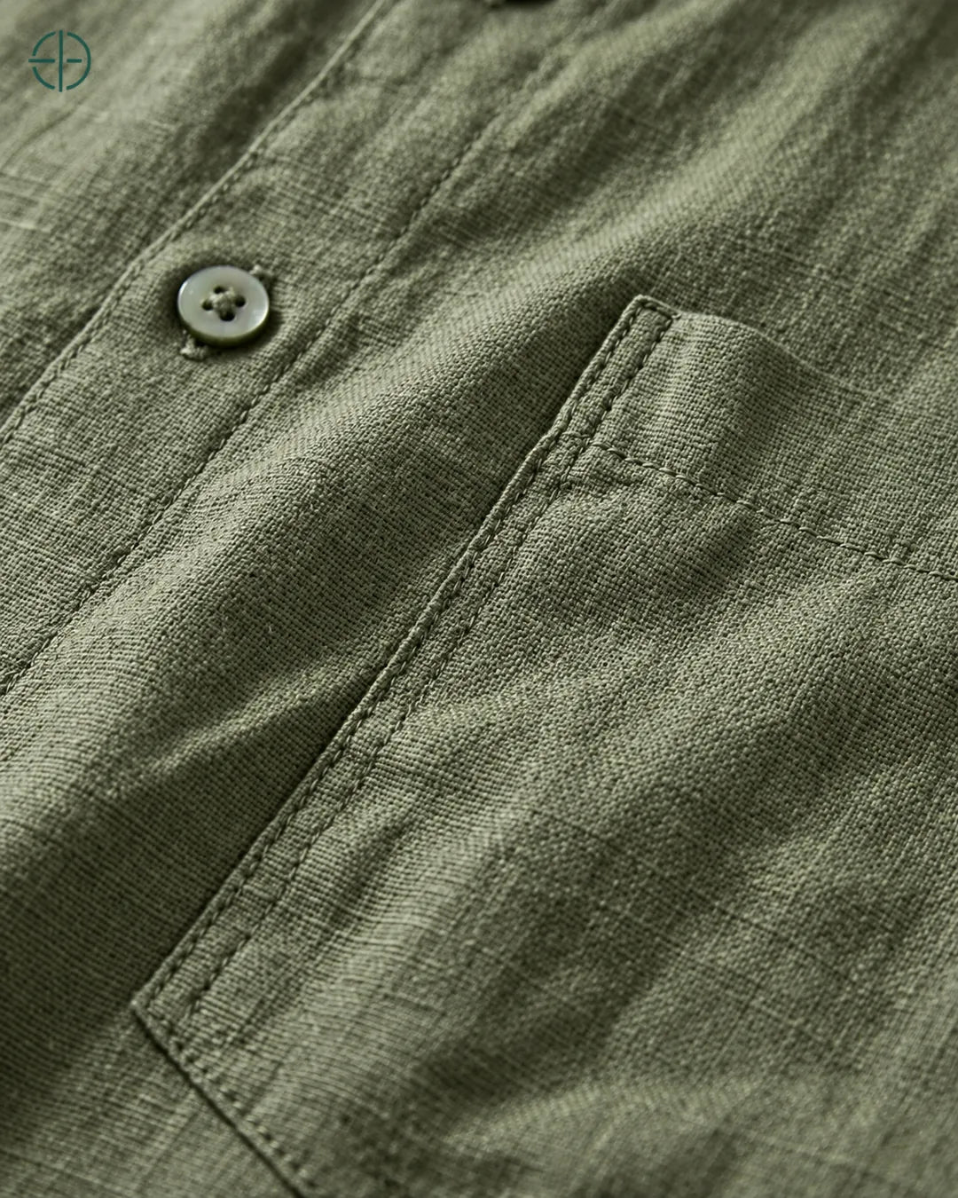 Camisa 100% Linho Belga Masculina, cor Verde, Detalhe aproximado do tecido e da costura no modelo, mostrando textura real, em estúdio profissional com fundo cinza ostra.